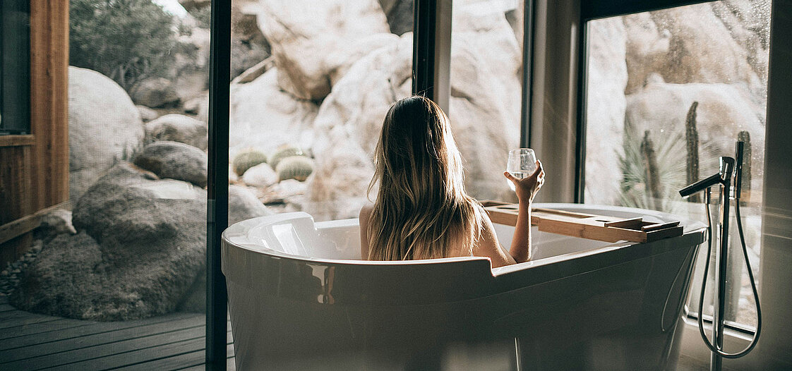 Ein Foto von einer Frau in einer freistehenden Badewanne.