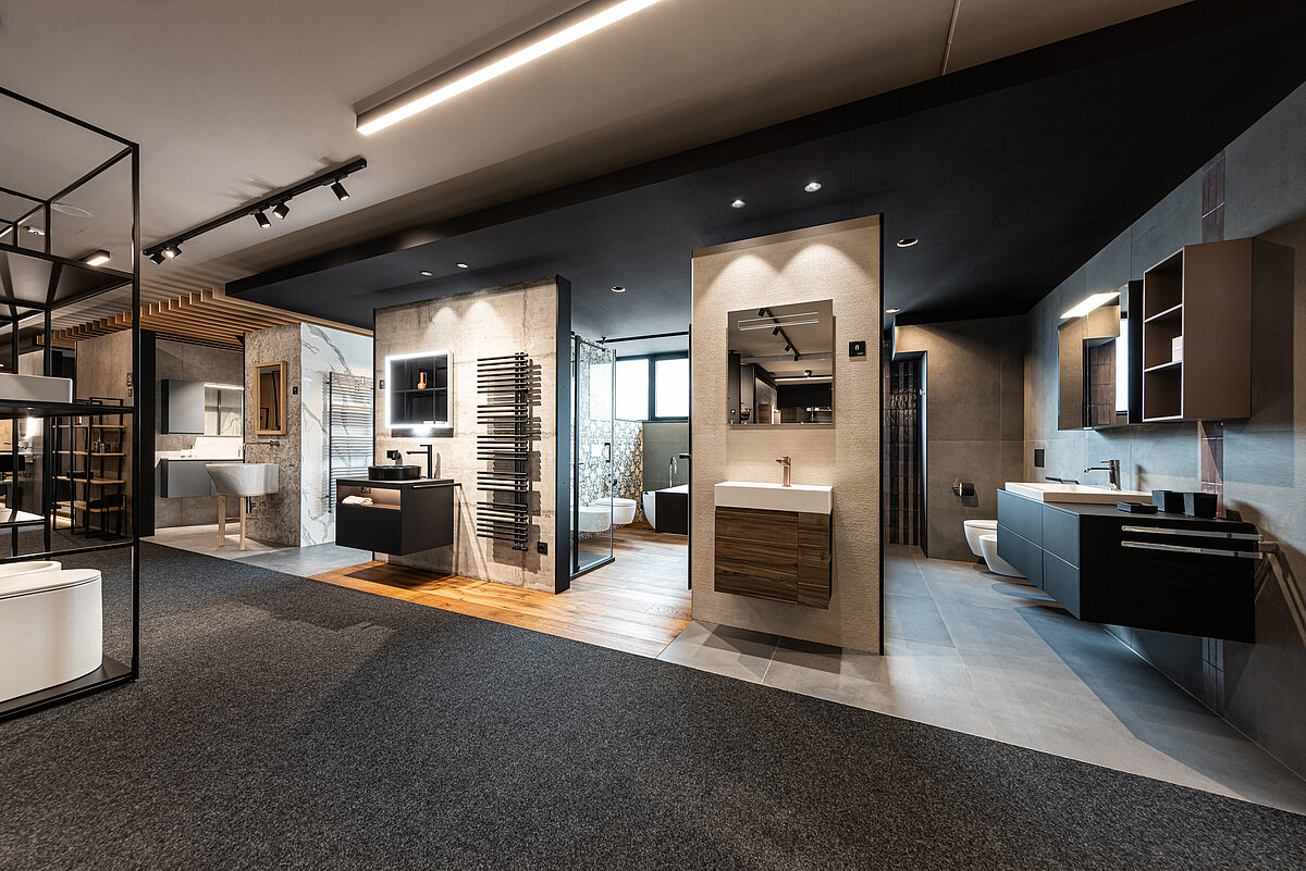Ein modernes Badezimmer-Showroom mit verschiedenen Ausstellungsstücken wie Waschbecken, Spiegeln und Schränken. Die Einrichtung ist in verschiedenen Stilen präsentiert, mit Akzentbeleuchtung und einer neutralen Farbpalette, die eine elegante Atmosphäre schafft.