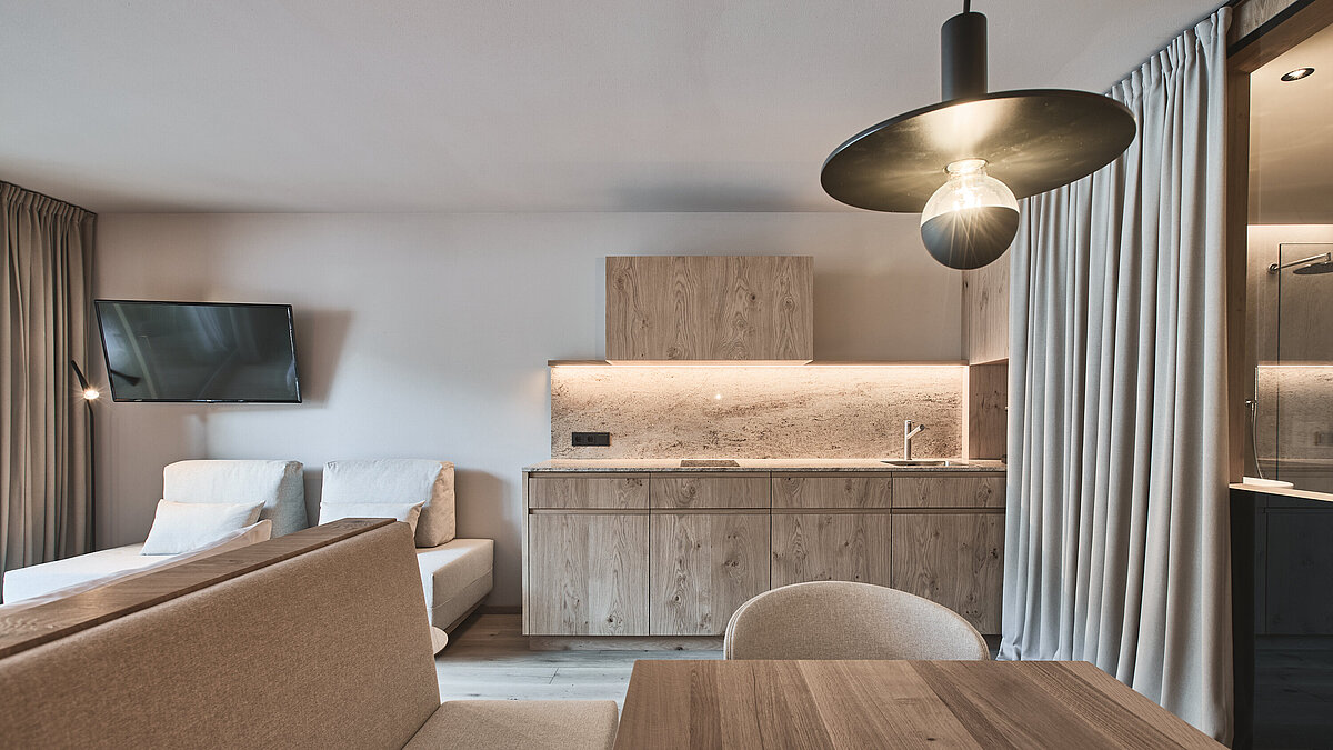 Moderne Badezimmertheke mit weißem Aufsatzwaschbecken, Seifenspender und verschiedenen Toilettenartikeln auf einem Tablett; grau strukturierte Wand und Holzregal mit weiteren Gegenständen darüber.