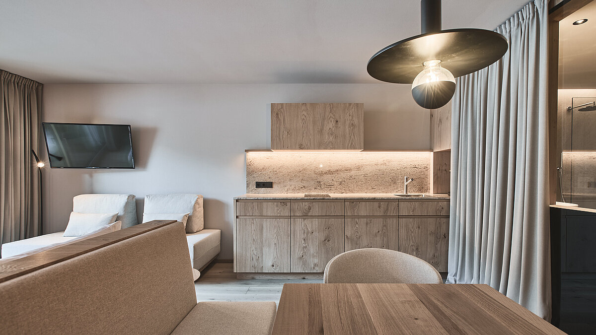 Moderne Badezimmertheke mit weißem Aufsatzwaschbecken, Seifenspender und verschiedenen Toilettenartikeln auf einem Tablett; grau strukturierte Wand und Holzregal mit weiteren Gegenständen darüber.